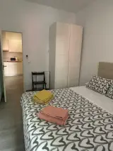Dormitorio del Apartamento Exterior con cama de matrimonio, armario blanco y toallas plegadas sobre la colcha